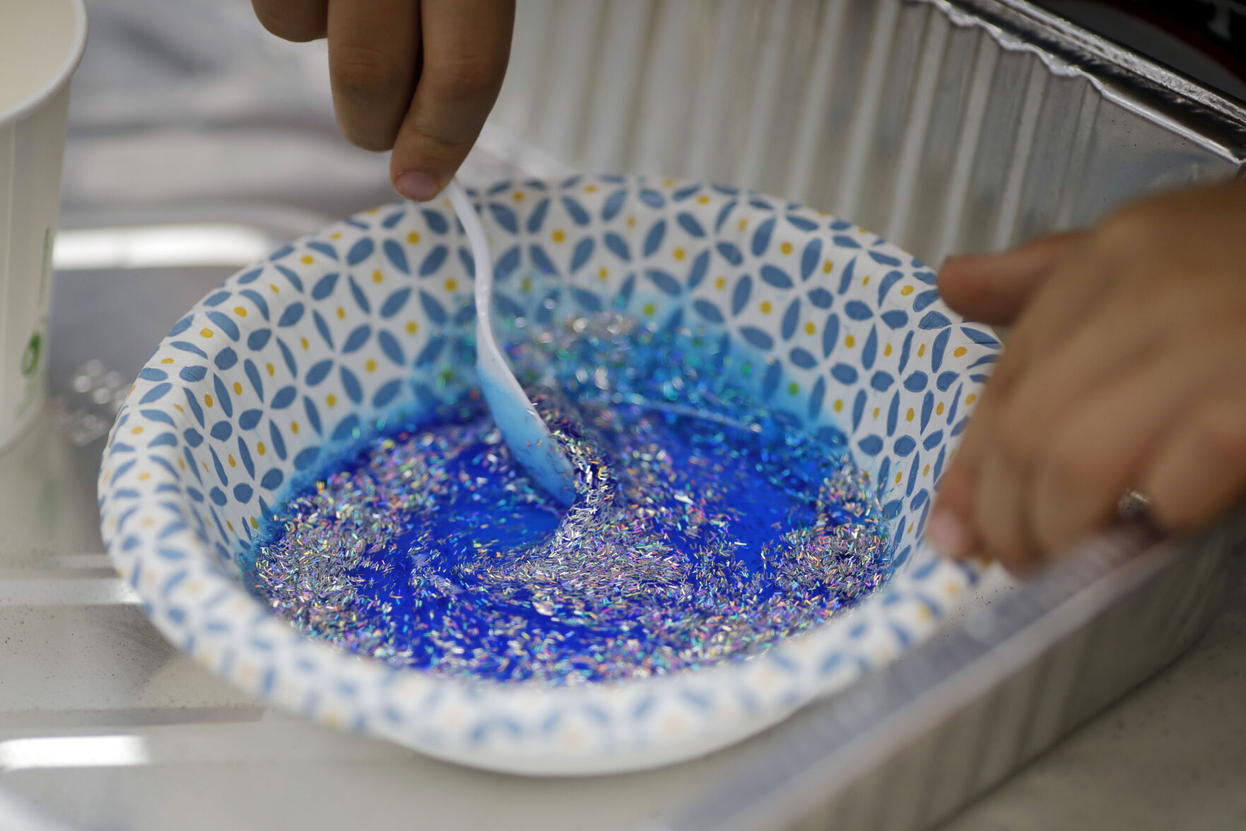 mixing glitter into blue mixture in bowl